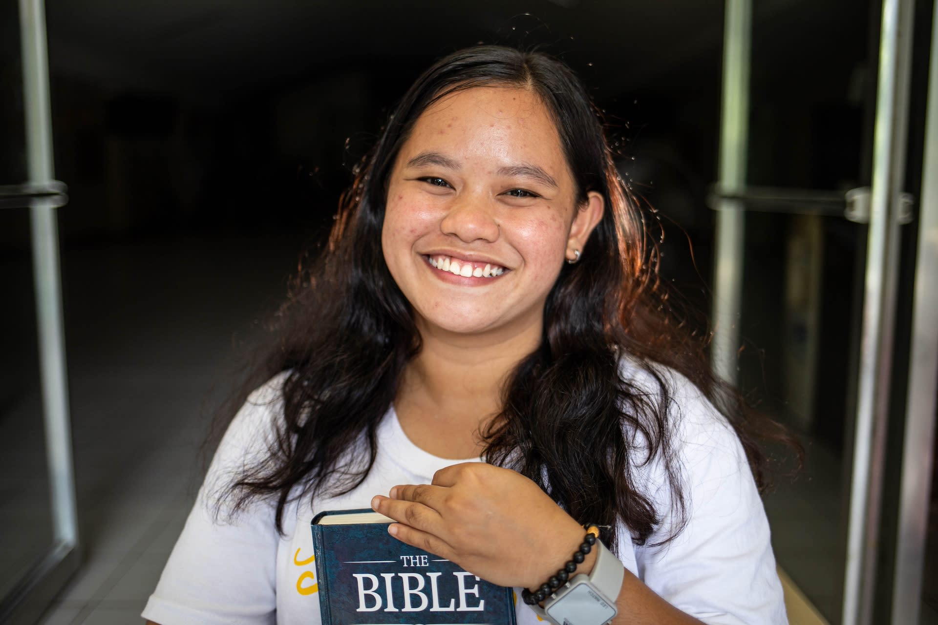 A young woman in the Philippines smiles and holds up her Bible.