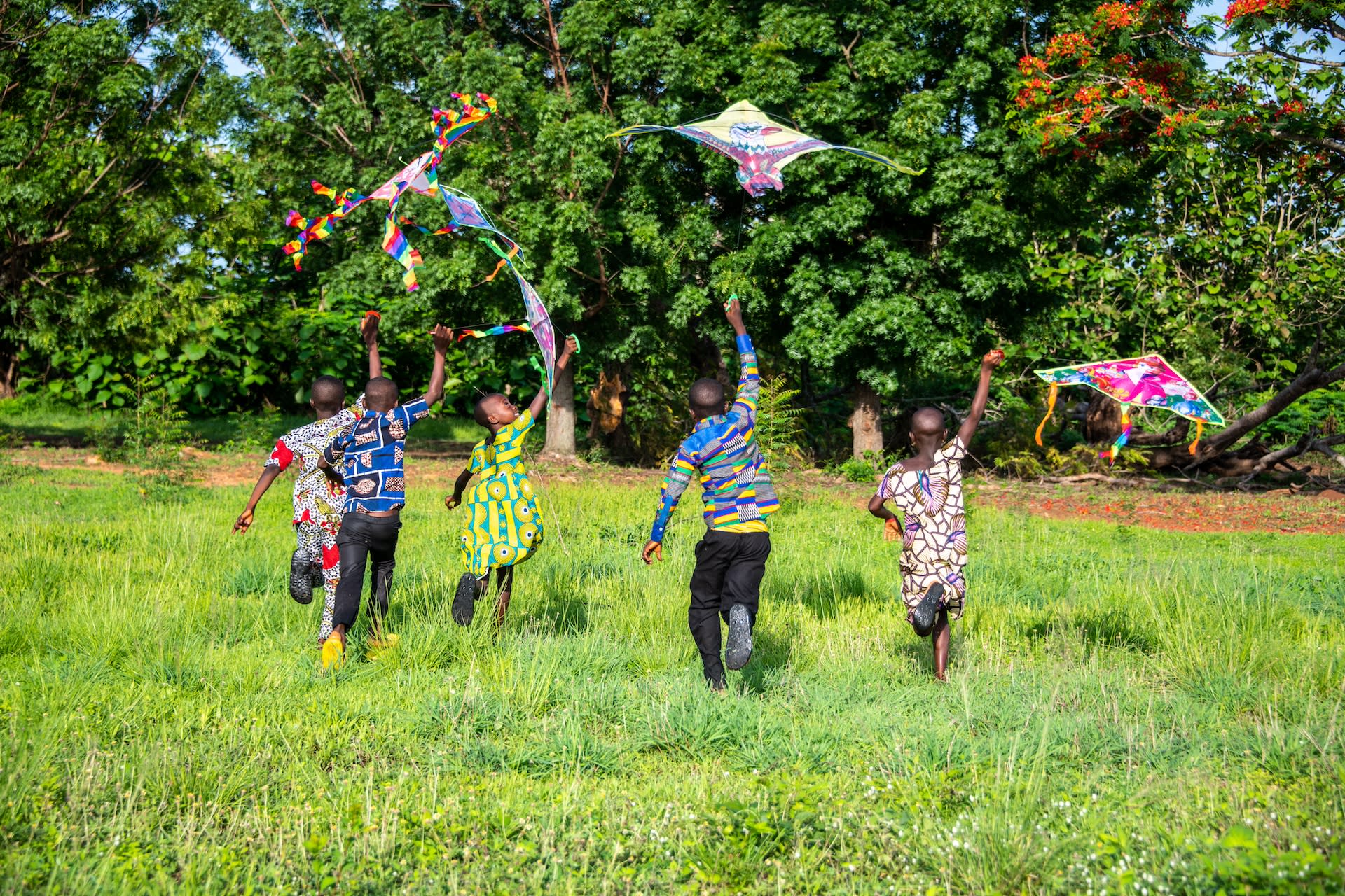 Children flying kites in a field in Togo.