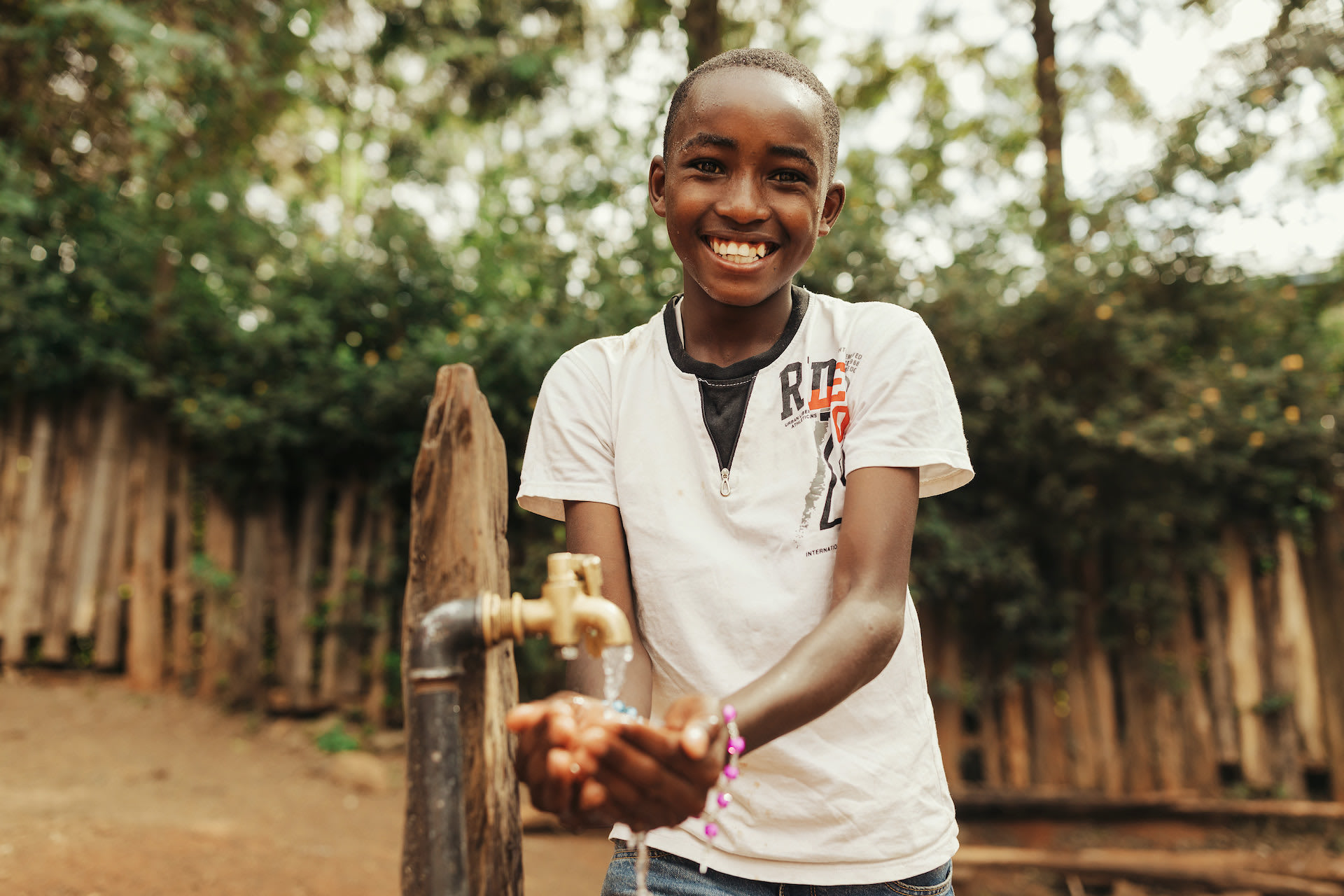 A boy getting water from an outdoor tap