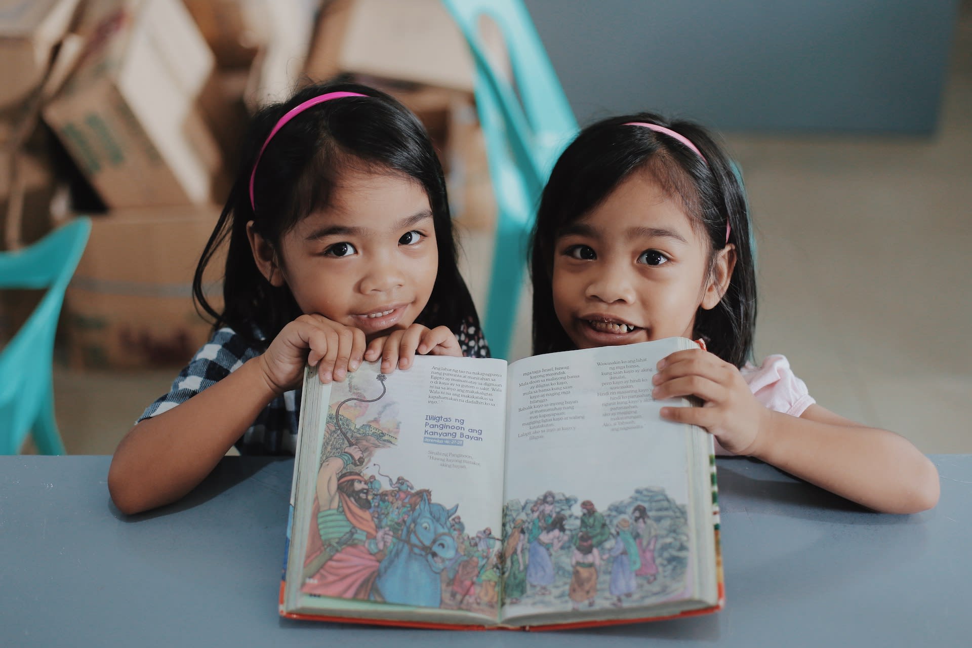 Two little girls smile as they read the Bible together