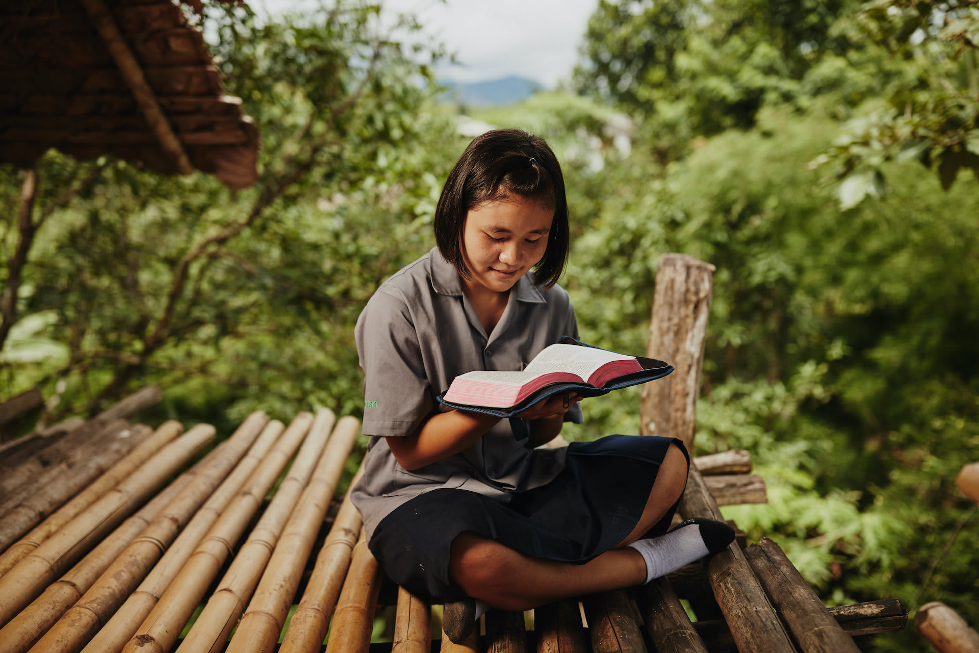 A girl sits outside reading her Bible.