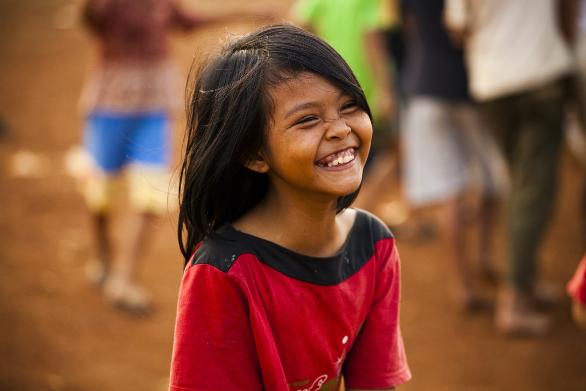 A young girl in a red shirt, laughing.