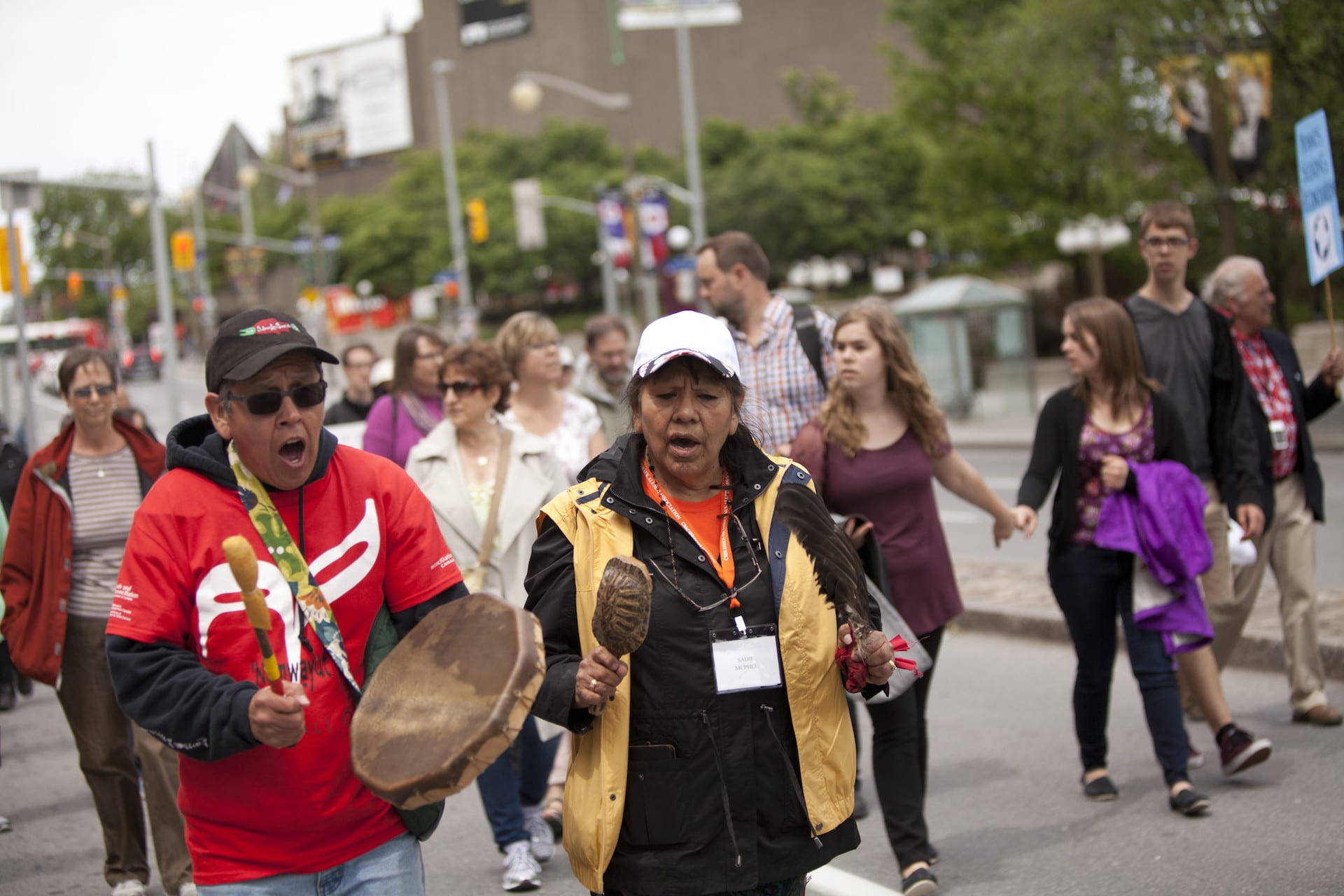 An Indigenous Elder sings and plays a drum during a walk for reconciliation.