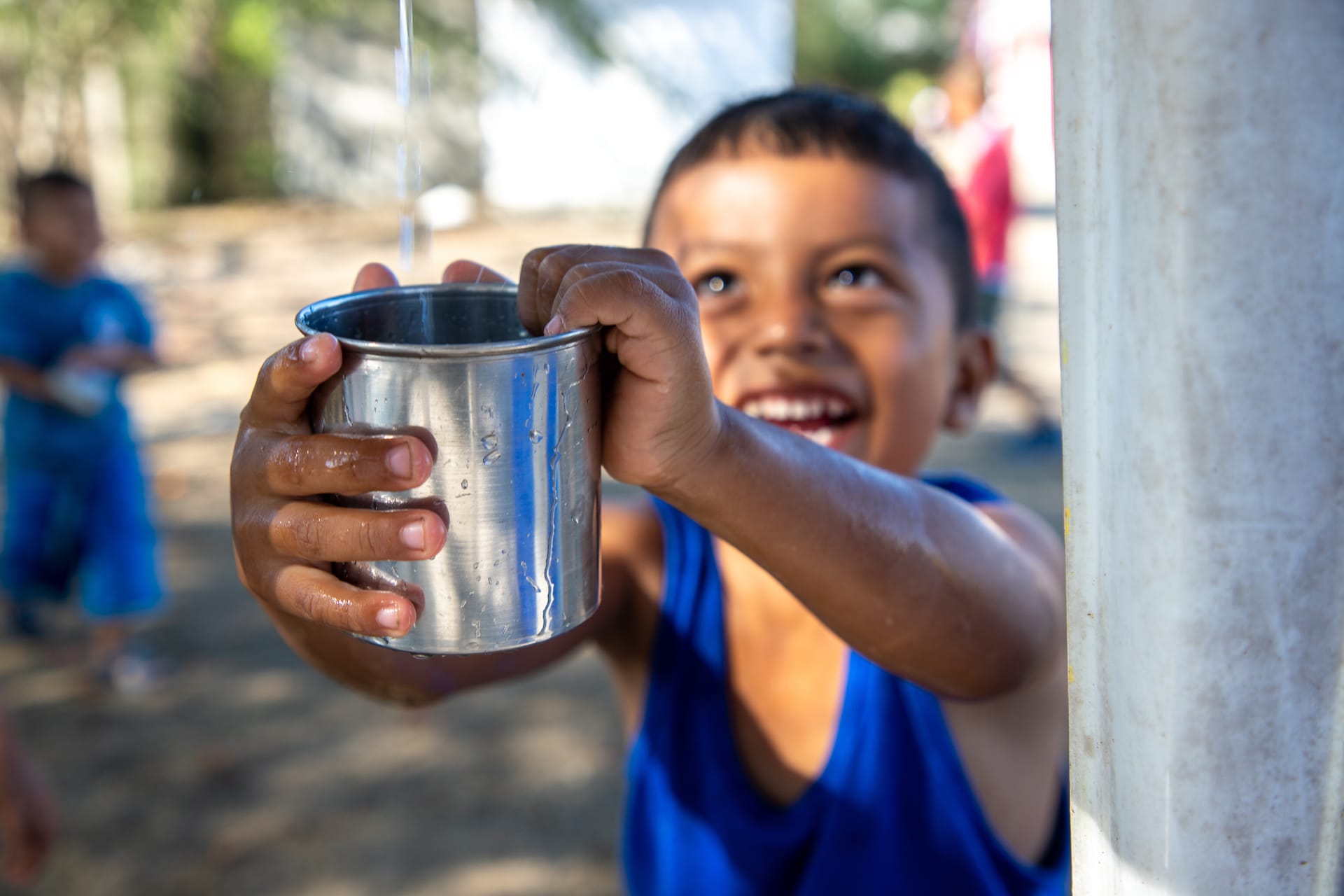A young boy, Jimmy, reaches out to fill a cup with clean water.