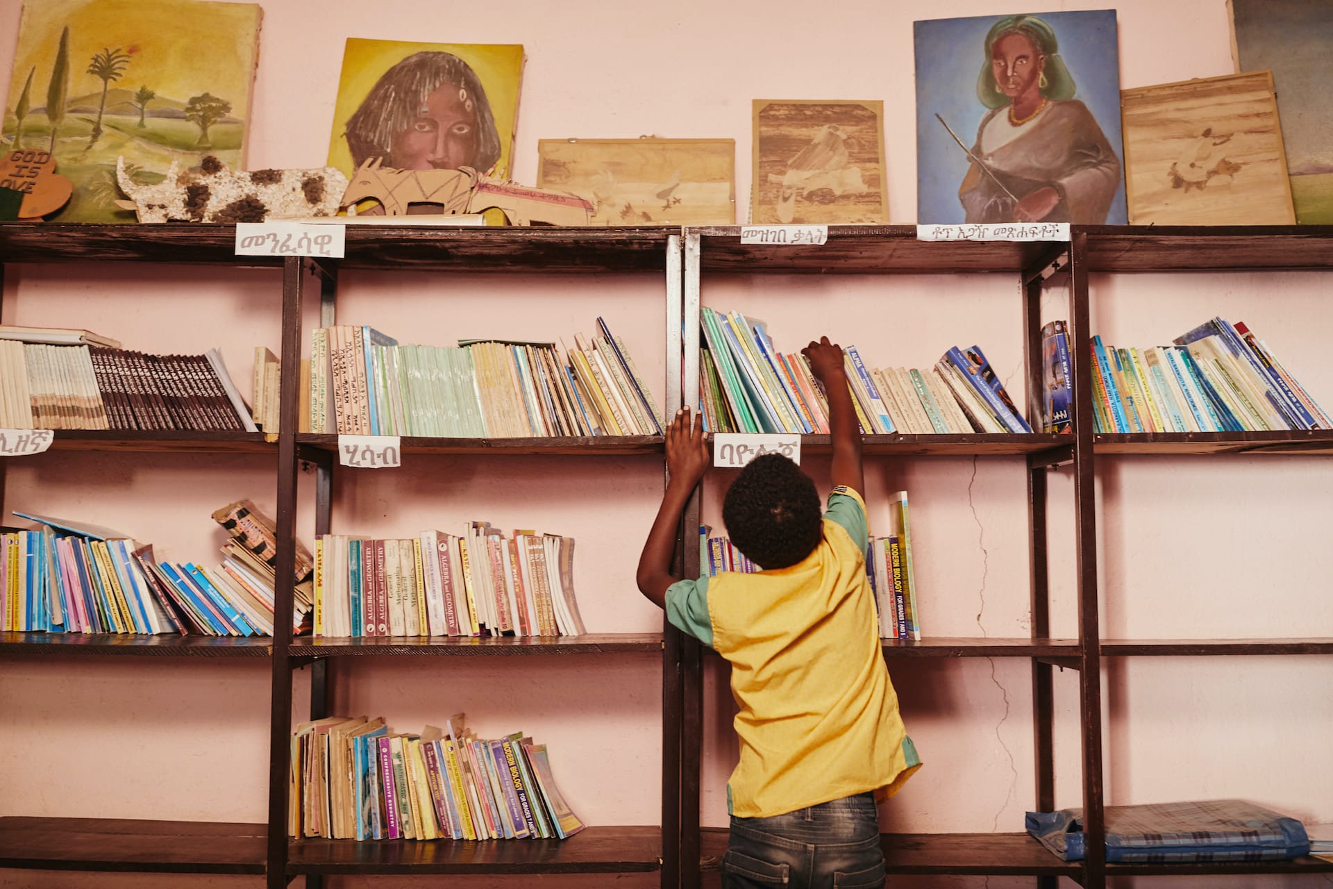 a child reaches for a book on a bookshelf.