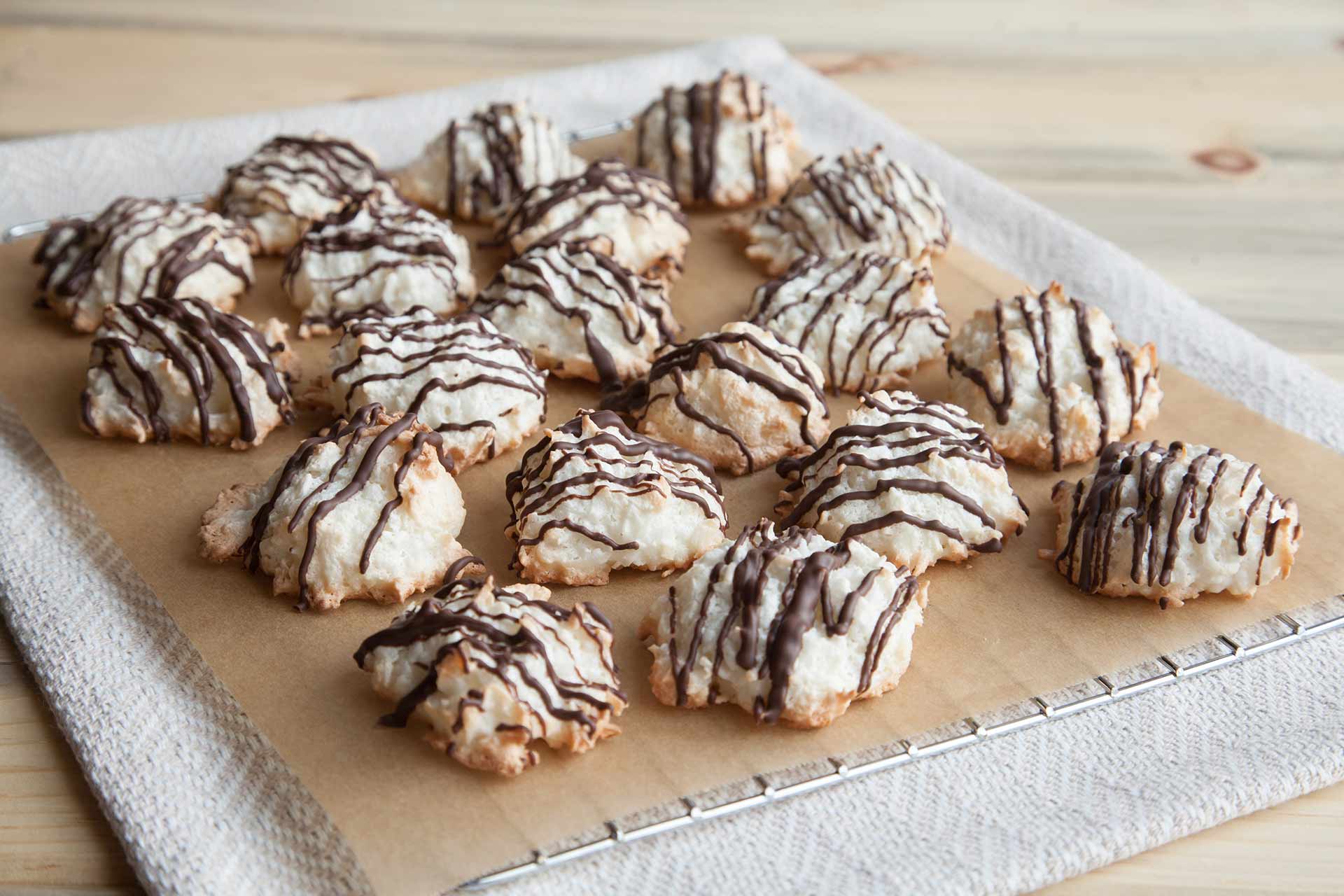 A plate of cookies drizzled with chocolate on a cooling rack.