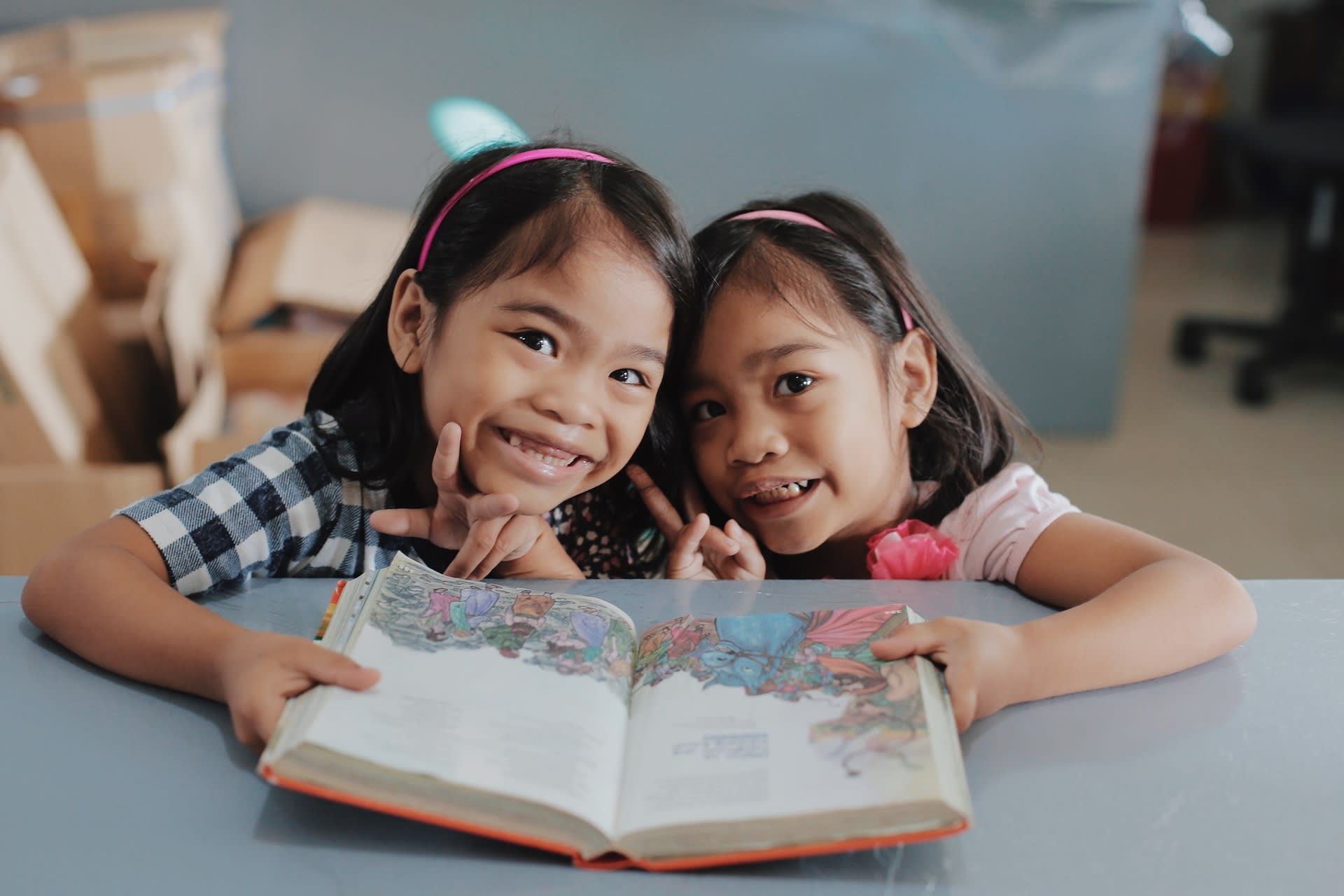 Two little girls smile as they read the Bible together