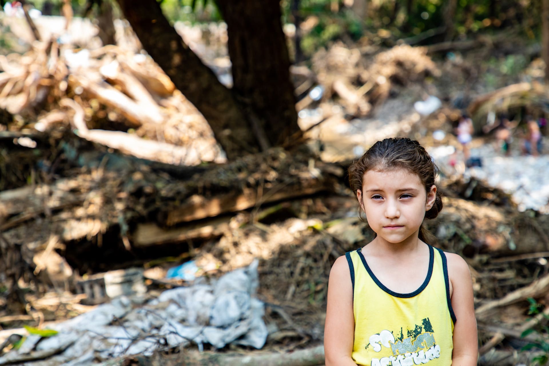 A young Honduran girl stands in the rubble of her home.