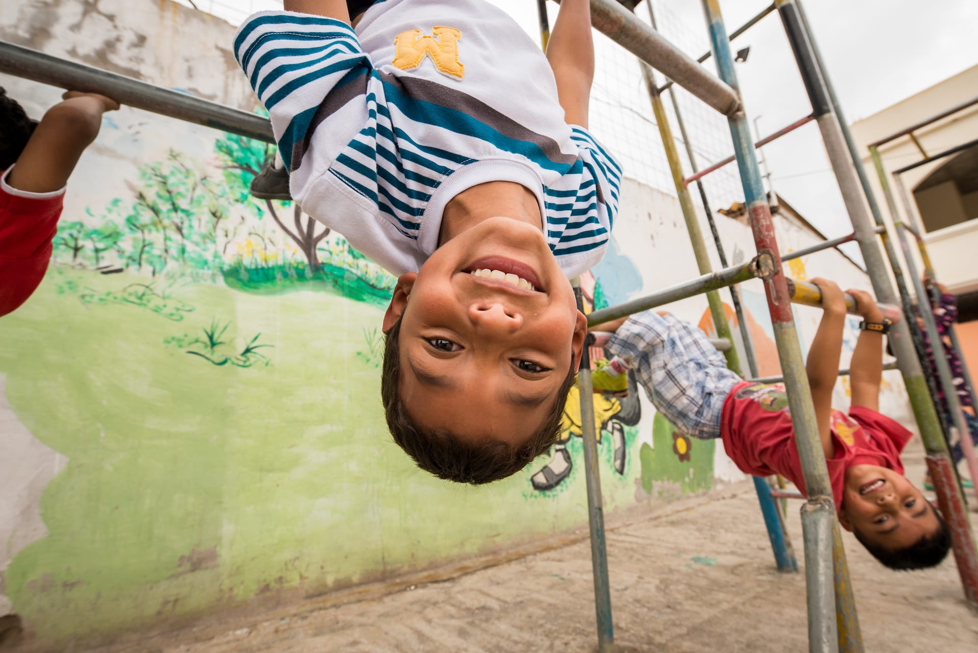 A boy hangs upside down from a playground structure.