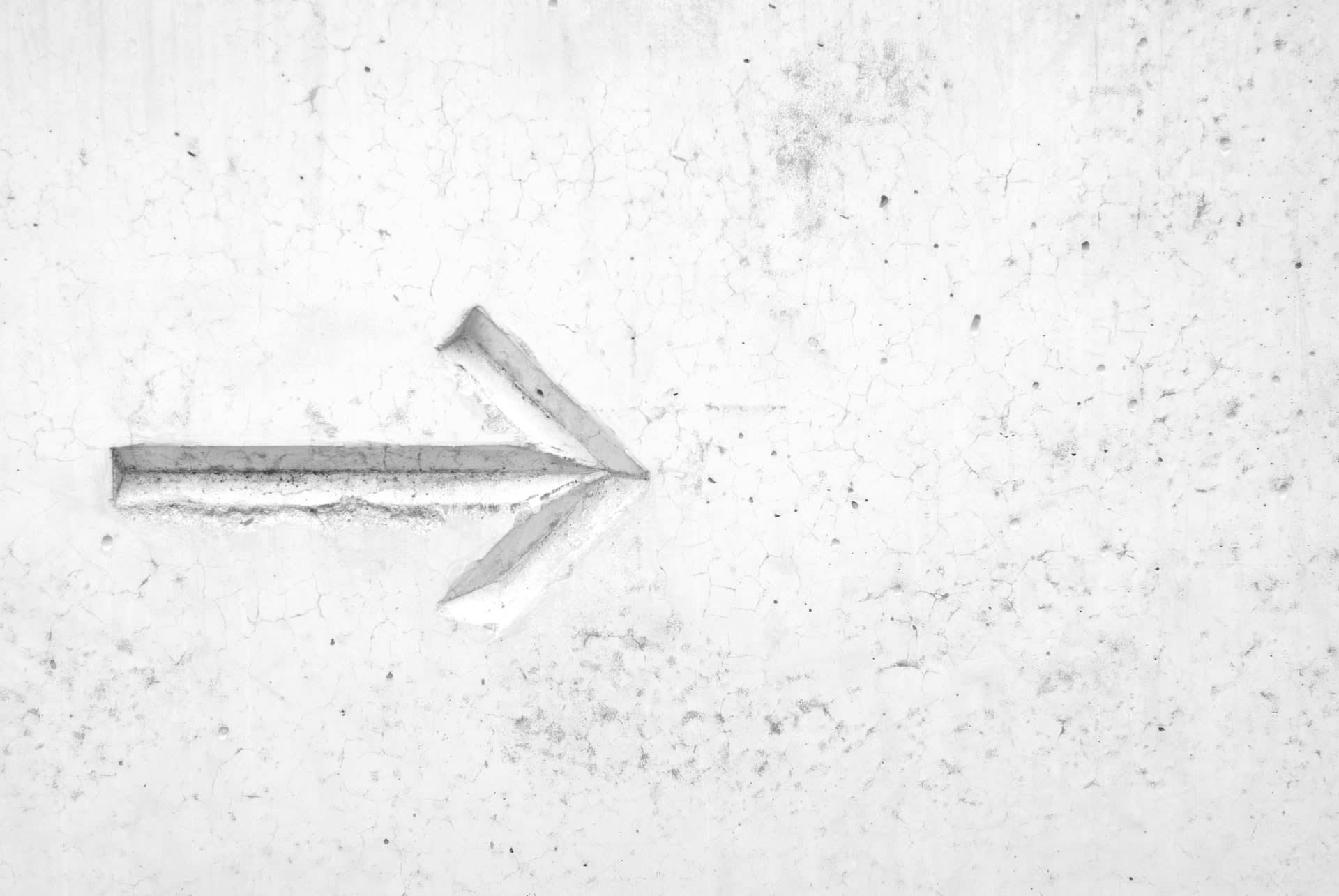 A white wall with an arrow carved into it.