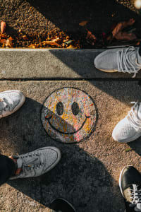 Two people stand beside a smiley face on the pavement