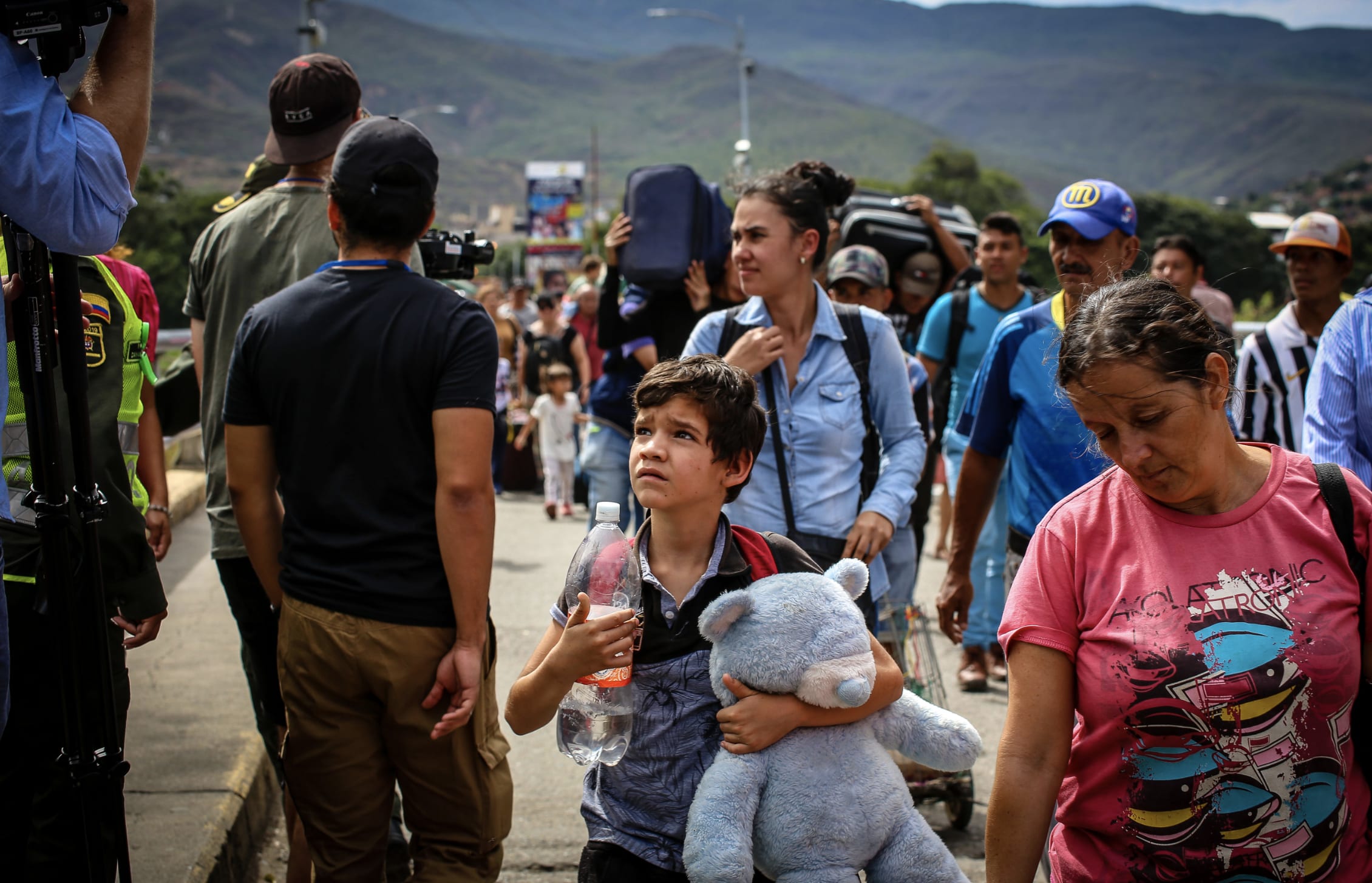 A young boy, teddy bear in hand, walks toward the Colombian border