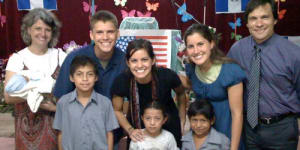 A family of eight stand together and pose for a photo.