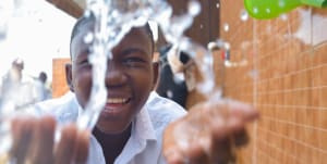 A boy smiling happily at clean tap water