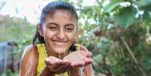 A girl holding some fresh water on her hand.