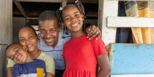 A man holding his family together, smiling happily.