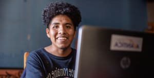 A boy with a laptop smiling happily