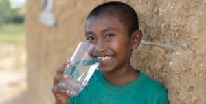 A child holding a cup of clean water with a big smile on his face