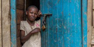 A girl standing beside a blue door smiling
