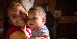 A mother holding her baby smiling happily.