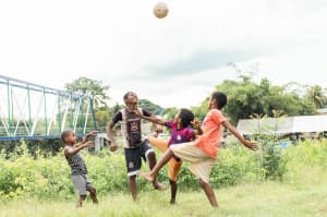 Four boys in Brazil playing soccer in a field next to the river that runs through their community.