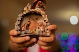 A child's hands holds a nativity set.