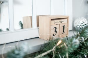 block calendar that reads December 31 sits on a fireplace mantle with garland and decorations