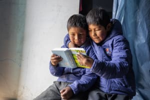 Two boys in Peru read a book together.
