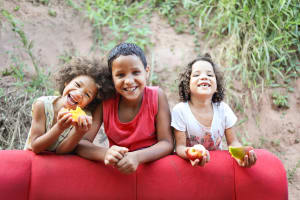 Three children and smiling and eating fruits.