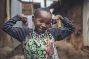 A boy stands flexing his arms.