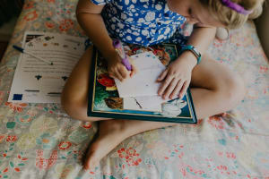 Sienna sits in her bedroom, drawing a picture to accompany a letter to her Compassion child, Praise.
