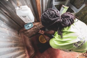 A woman washes her hands using a homemade device known as a 'leaky tin'.