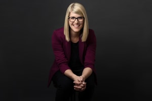 Allison is pictured sitting on a stool with her hands clasped together.