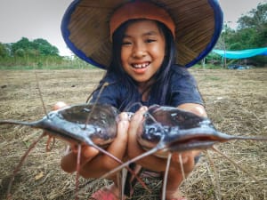 Meisy holds two catfish in her hands.