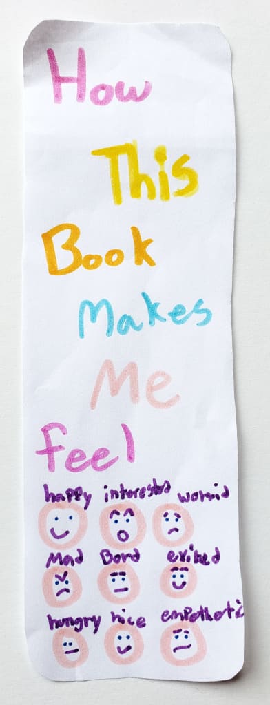 A hand-drawn bookmark with the words "How this book makes me feel" and emojis drawn on it.