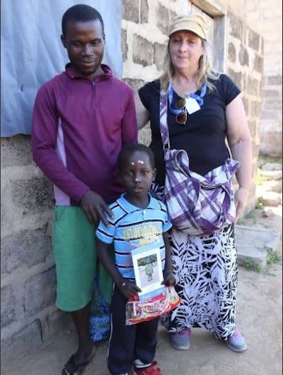 A woman stands with a boy and his father in front of their home.