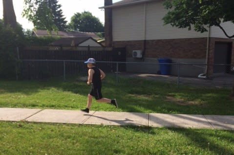 Boy in a white cap is running on a sidewalk