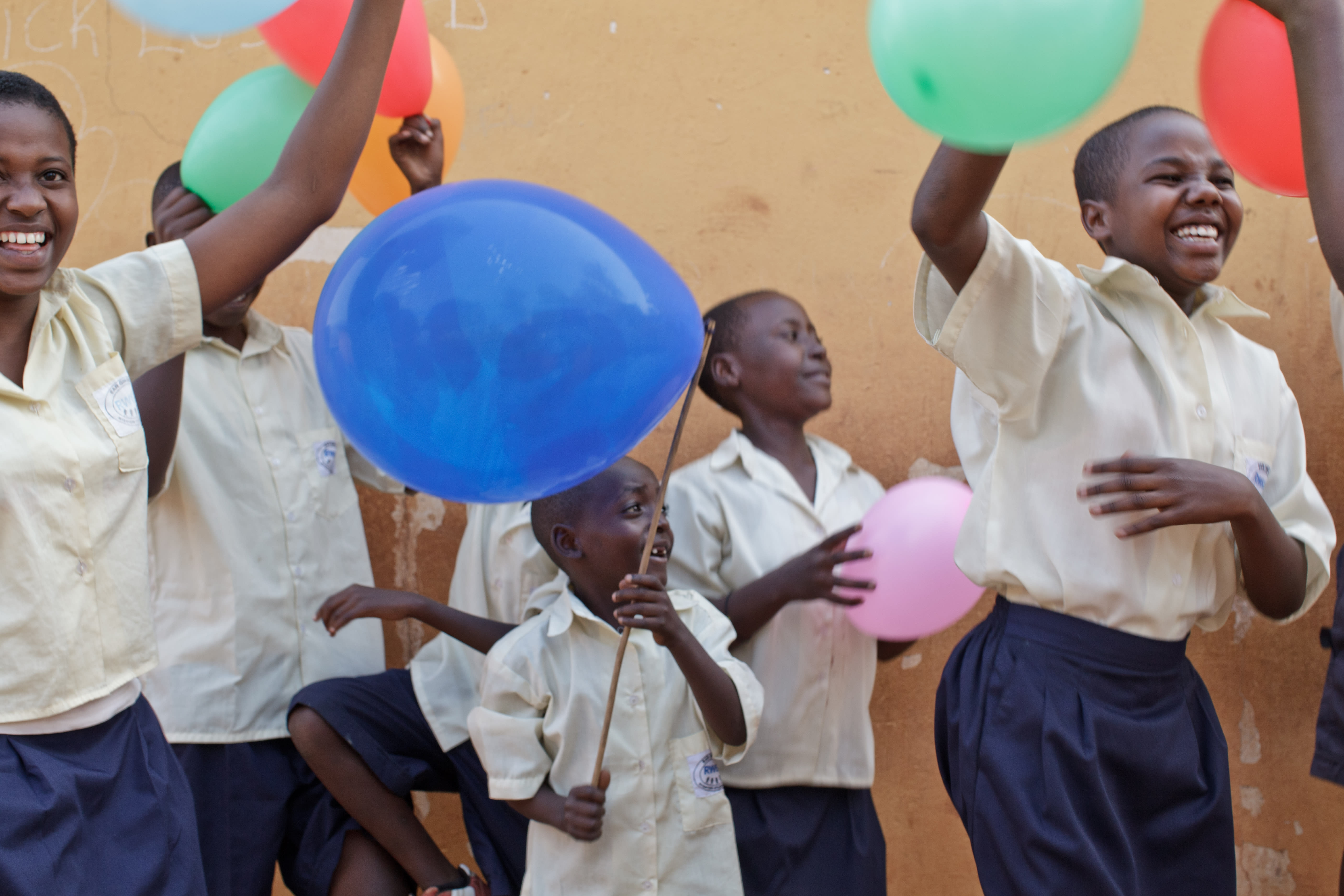 A group of children plays with multicolour balloons in Rwanda.