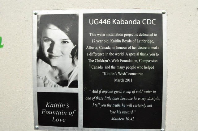 A plaque with a picture of a young girl that reads, "Kaitlin's Fountain of Love" and describes how she helped fund the well for this community.