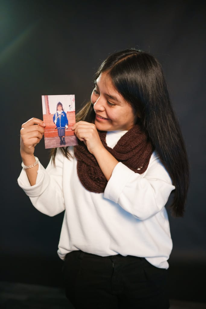 Liz, a young Peruvian woman, holds up a picture of her a a sponsored child