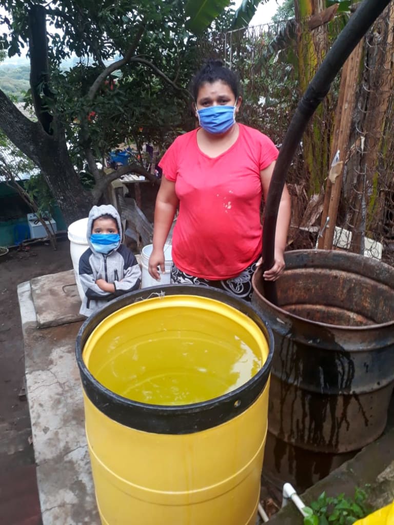 Petrona fills up her barrels with water from the water tank truck that Compassion provided.
