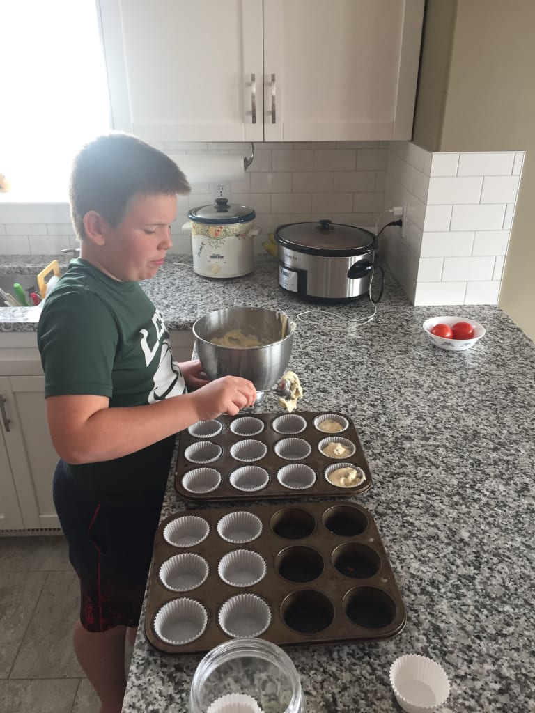 Jacob fills muffin tins with batter in his kitchen.