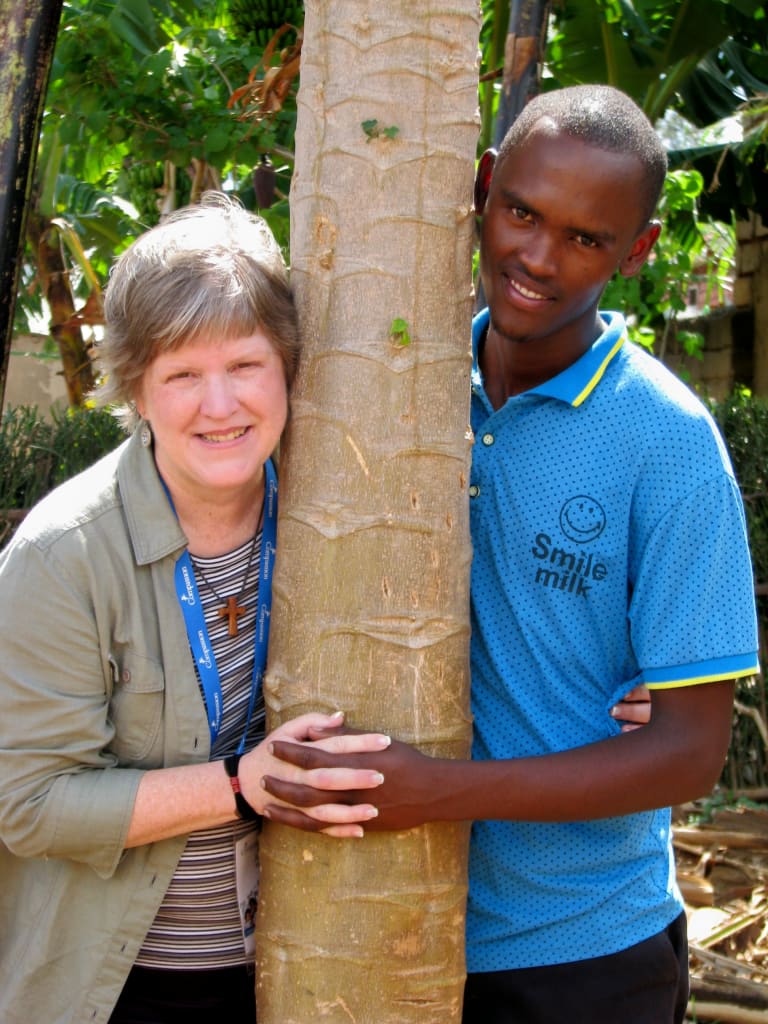 Judy poses around a tree with her sponsor child.