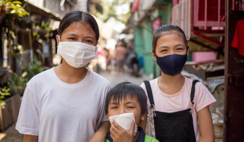 Three children standing together wearing masks.