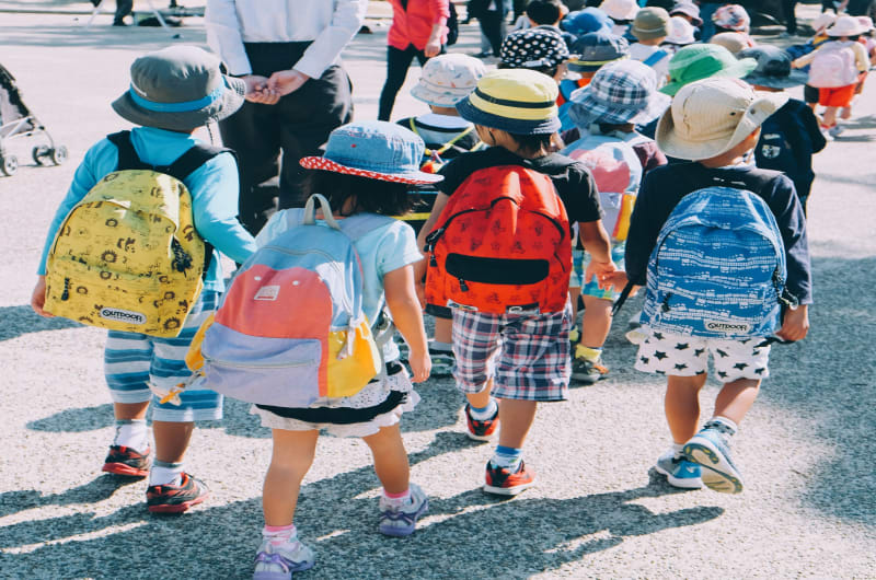 Four kids walk away from the camera wearing backpacks