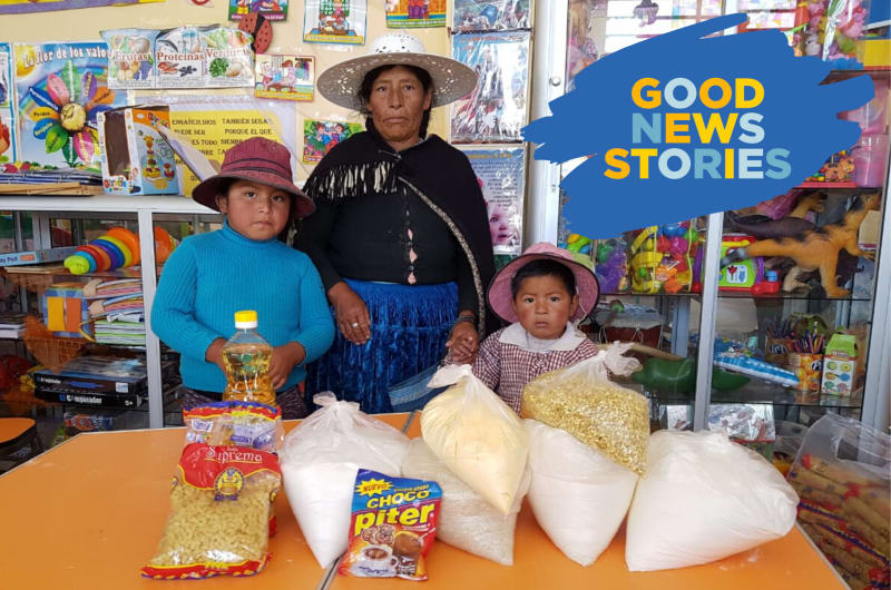 A woman and two children pose with a grocery delivery provided by Compassion.