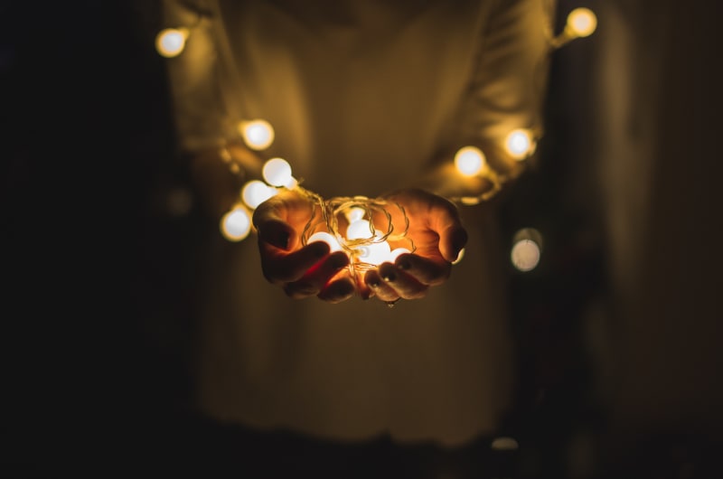 child holds christmas lights in their hand