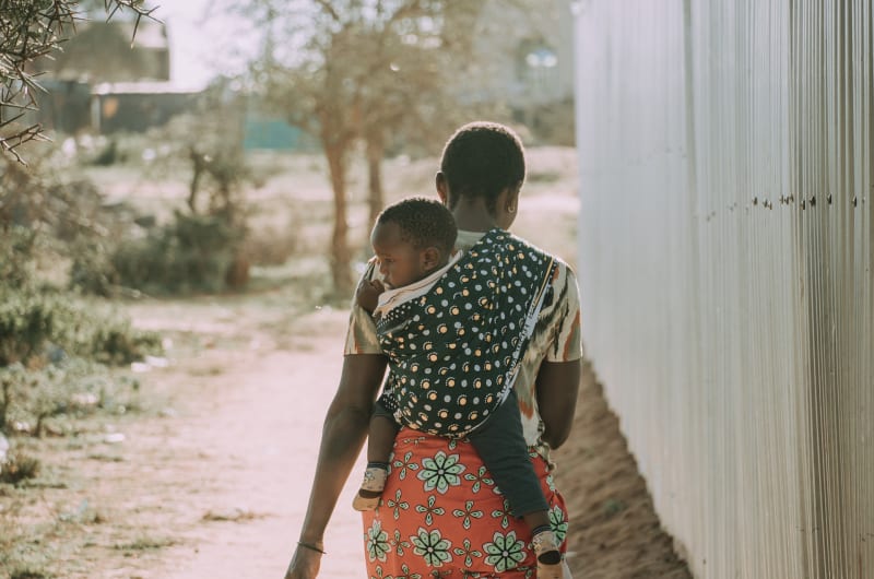 Woman carries baby on her back.