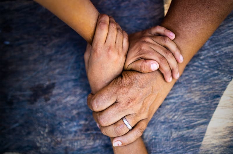 A close up of two hands intertwined on a mother's lap.