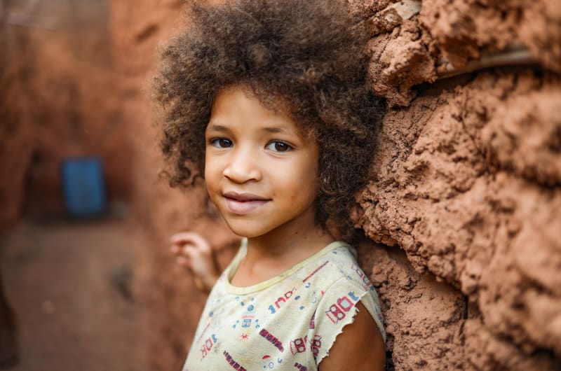 Emelly, in Brazil, is outside leaning against a brown wall.